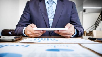 multitasking-handsome-young-man-working-with-touchpad-while-sitting-couch-office-financial-statistic-graph (1)
